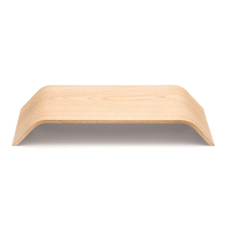 May include: A light wood laptop stand with a curved design. The stand is made of natural wood and has a smooth finish.