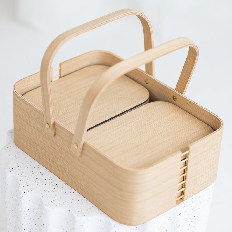May include: A wooden basket with two compartments and two handles. The basket is made of light wood and has a natural finish.
