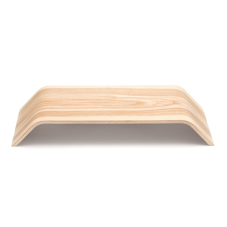 May include: A natural wood laptop stand with a curved design. The stand is made of light wood with a natural grain pattern.