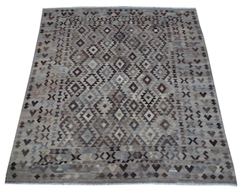 May include: A brown and gray area rug with a geometric pattern. The rug has a diamond pattern with a variety of shades of brown and gray.