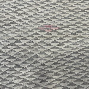 May include: A close-up of a grey and white fabric with a repeating pattern of small, stylised clouds. The fabric has a subtle texture and a slightly faded appearance.