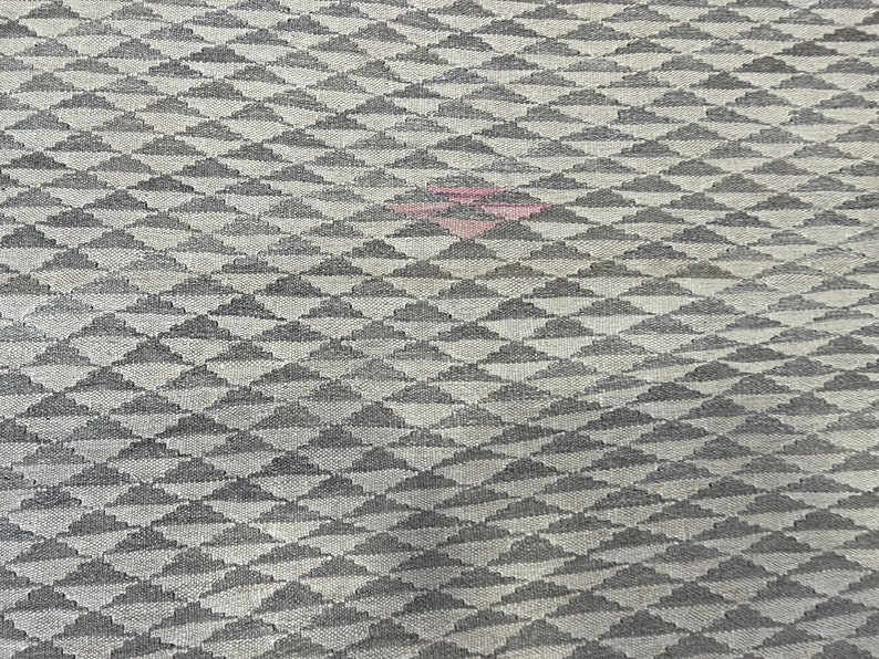 May include: A close-up of a grey and white fabric with a repeating pattern of small, stylised clouds. The fabric has a subtle texture and a slightly faded appearance.