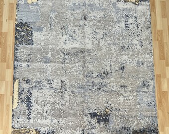 Puede incluir: Alfombra de área abstracta con un esquema de color gris, azul y beige. La alfombra tiene un aspecto desgastado y texturizado con un diseño moderno.