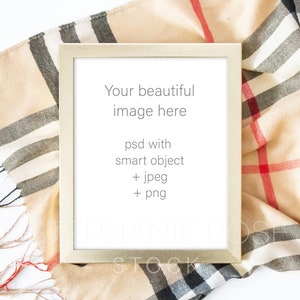 May include: A gold-colored picture frame with a white mat and a white background. The frame is sitting on a beige and black plaid fabric. The text inside the frame reads "Your beautiful image here psd with smart object + jpeg + png".