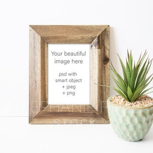 Op de afbeelding: Een rustieke houten lijst met een witte passe-partout en tekst die luidt "Your beautiful image here psd with smart object + jpeg + png". Rechts van de lijst staat een kleine groene potplant.