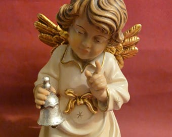 May include: A cream-coloured ceramic angel figurine with golden wings and a silver bell. The angel wears a cream-coloured robe with a golden bow and star accents. The figurine has a peaceful expression and is a decorative item.