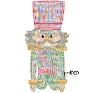 May include: A whimsical nutcracker with a colourful, glittery hat and a teal, pink and gold patterned uniform. The nutcracker has a grey beard and moustache, and a pink face.