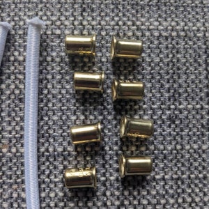 May include: Eight gold metal cord ends for use in jewelry making or other crafts.