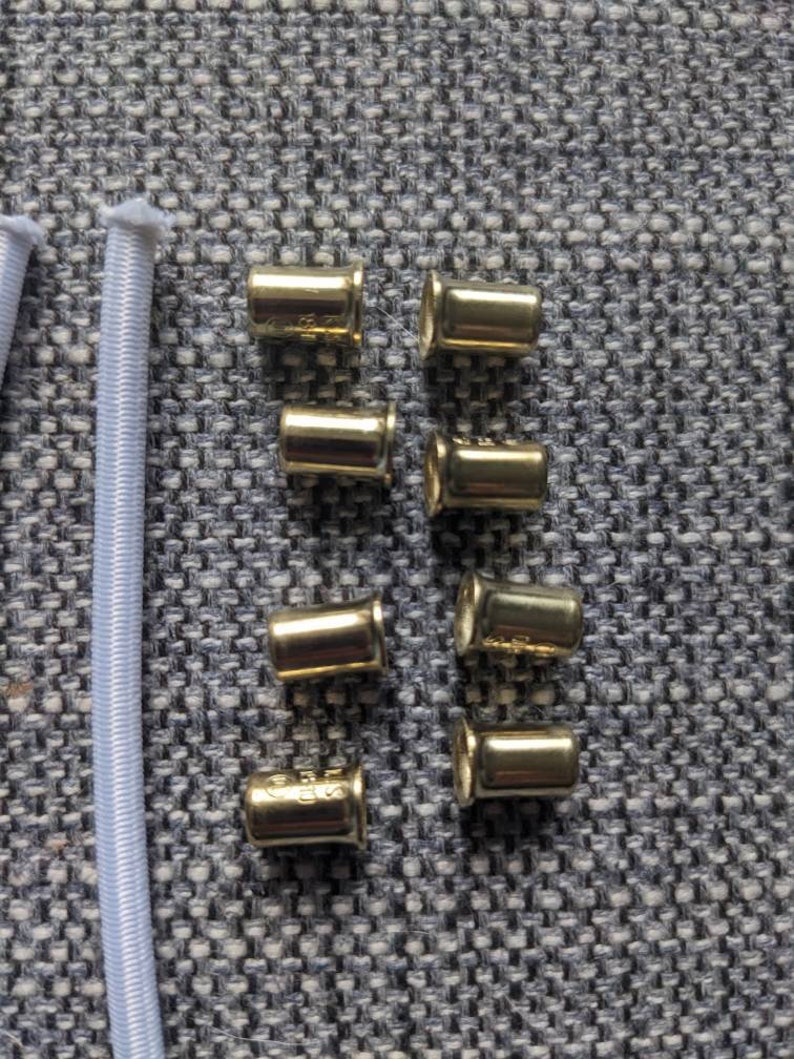 May include: Eight gold metal cord ends for use in jewelry making or other crafts.
