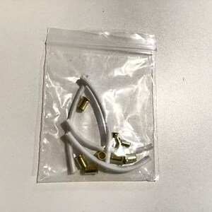 May include: A clear plastic bag containing white plastic earbud tips and gold metal earbud filters.