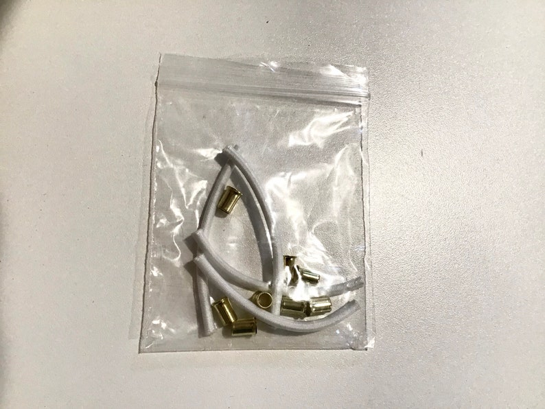 May include: A clear plastic bag containing white plastic earbud tips and gold metal earbud filters.