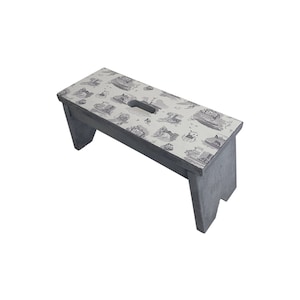 Peut inclure: Un tabouret en bois gris avec un dessus blanc orn&eacute; d'un motif toile noir et blanc. Le tabouret a une poign&eacute;e d&eacute;coup&eacute;e sur le dessus.