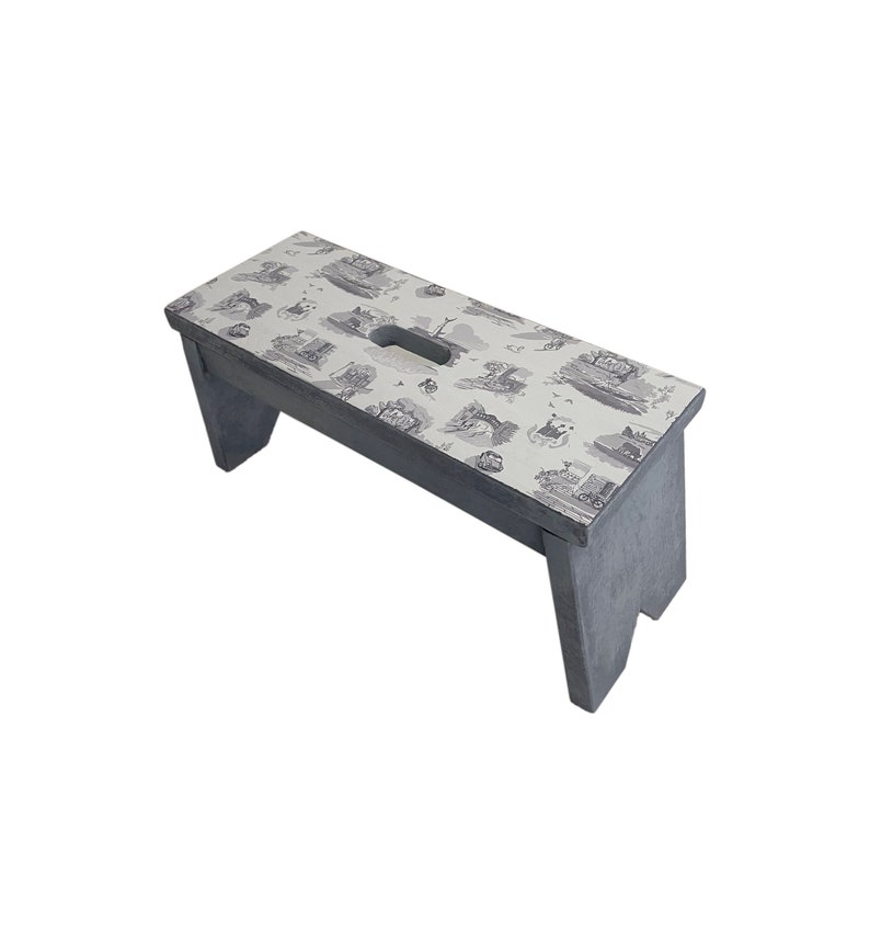 Peut inclure: Un tabouret en bois gris avec un dessus blanc orn&eacute; d'un motif toile noir et blanc. Le tabouret a une poign&eacute;e d&eacute;coup&eacute;e sur le dessus.