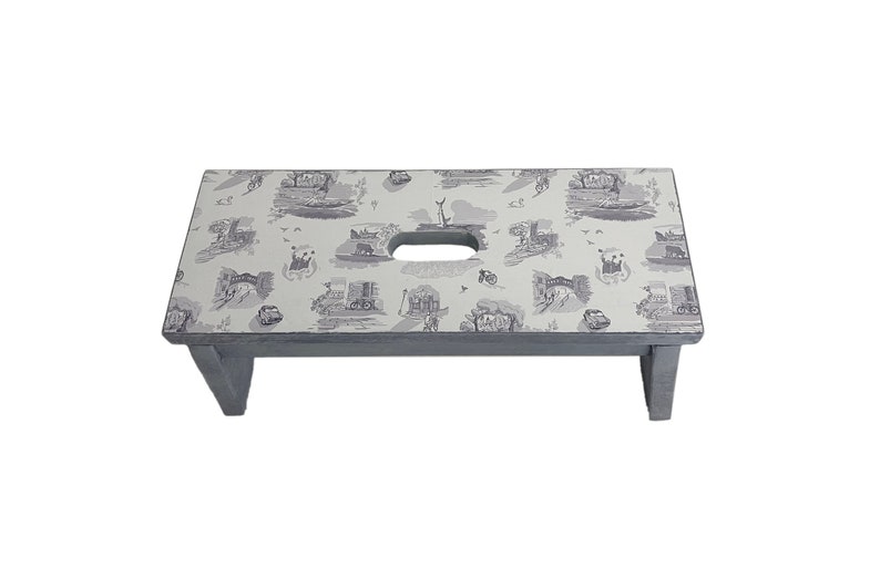 Peut inclure: Un tabouret en bois gris avec un dessus blanc orn&eacute; d'un motif r&eacute;p&eacute;titif d'illustrations noires et blanches. Le dessus a une poign&eacute;e d&eacute;coup&eacute;e.