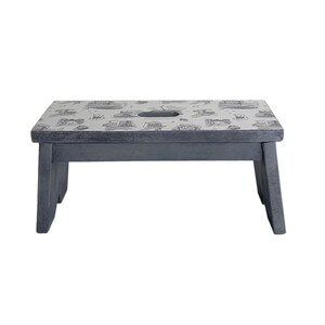 Peut inclure: Un petit tabouret en bois gris avec un dessus blanc orn&eacute; d'un motif noir et blanc. Le tabouret a une d&eacute;coupe au centre du dessus.