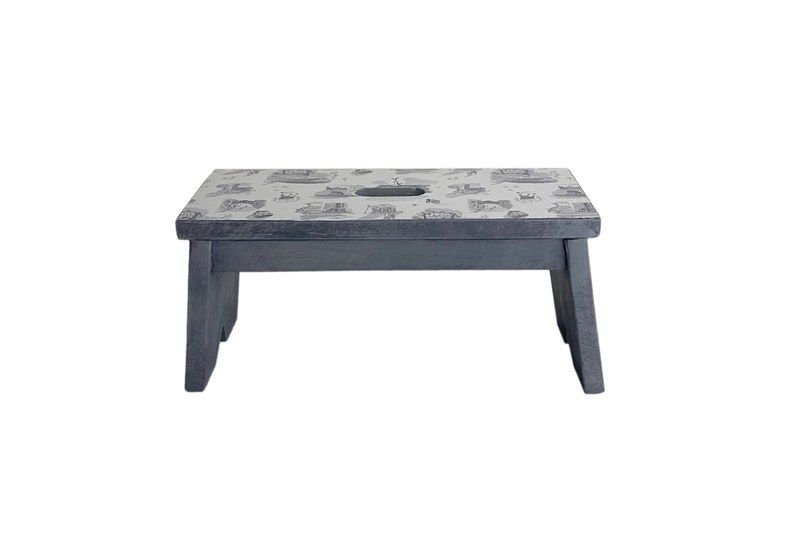 Peut inclure: Un petit tabouret en bois gris avec un dessus blanc orn&eacute; d'un motif noir et blanc. Le tabouret a une d&eacute;coupe au centre du dessus.