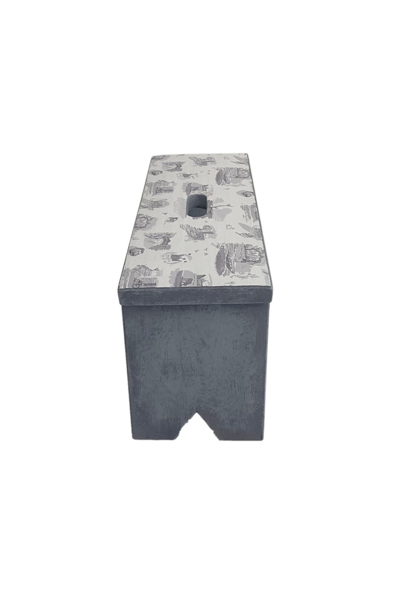 Peut inclure: Un tabouret en bois gris avec un dessus blanc orn&eacute; d'un motif noir et blanc. Le tabouret a une poign&eacute;e d&eacute;coup&eacute;e sur le dessus.