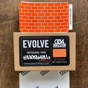 May include: An assortment of labels and stickers. The top sticker has a brick pattern and the text "-RIP AND STICK-". Below is a brown box with the text "EVOLVE PROFESSIONAL GRADE SARASHELL LABELS WWW.004CONNEC.COM". Below the box are white labels with the text "EVOLVE SARASHELL LABELS".