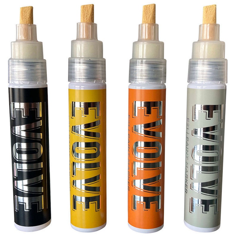 Op de afbeelding: Vier verfmarkers met zilveren doppen en houten toppen. De markers zijn gelabeld "EVOLVE" in zilveren letters. De markers zijn zwart, geel, oranje en grijs.