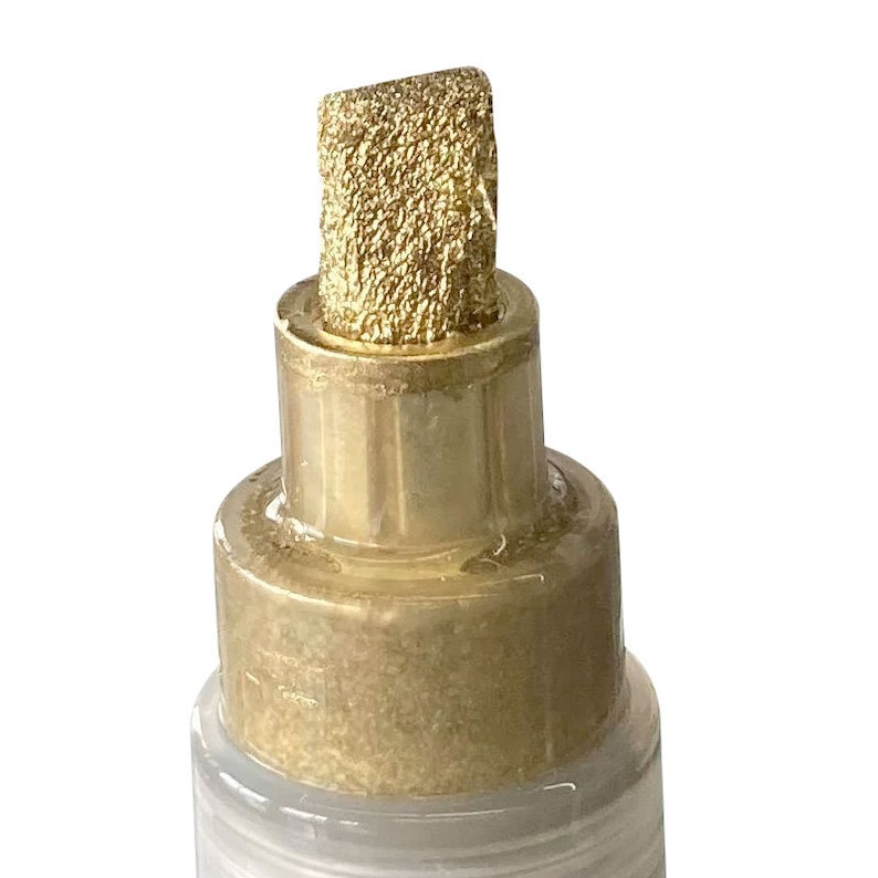 Op de afbeelding: Close-up van de punt van een gouden verfmarker met een fijne punt.