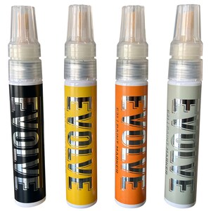 Op de afbeelding: Vier verfmarkers met zilveren opschrift "EVOLVE" aan de zijkant. De markers zijn zwart, geel, oranje en grijs.