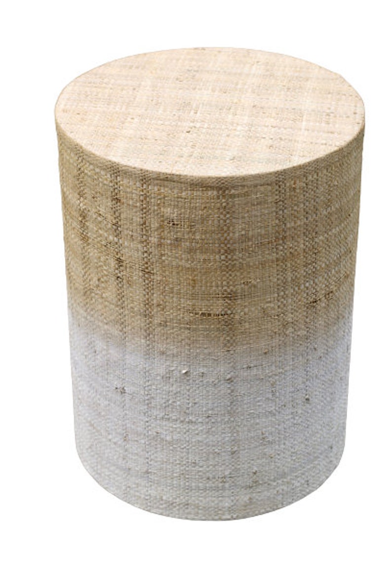 May include: A round, woven stool with a white ombre effect. The stool is made of natural fibers and has a rustic, farmhouse style.