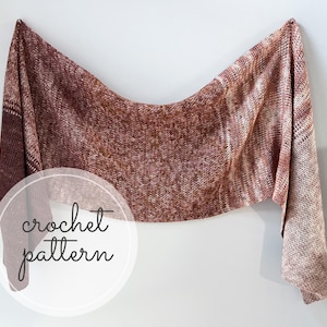 Pode incluir: Um xale de crochê marrom e branco com um padrão texturizado. O xale está drapeado em uma parede branca com o texto "crochet pattern" em um círculo.