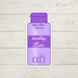 K&ouml;nnte beinhalten: Ein violetter Aufkleber mit dem Text "knotting Lube" in einer stilisierten Schriftart. Der Aufkleber enth&auml;lt auch den Text "Alpha Omega Dynamics" und ein Symbol aus zwei Herzen &uuml;ber den griechischen Buchstaben Alpha und Omega.