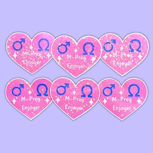 K&ouml;nnte beinhalten: Sechs rosa herzf&ouml;rmige Aufkleber mit wei&szlig;em Rand. Jeder Aufkleber zeigt ein blaues M&auml;nnlichkeitssymbol und ein blaues Omega-Symbol. Der Text "M-Preg Enjoyer" ist auf jedem Aufkleber in Wei&szlig; geschrieben.