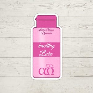 K&ouml;nnte beinhalten: Ein rosa Aufkleber in Form einer Flasche mit Klappdeckel. Der Aufkleber tr&auml;gt die W&ouml;rter "Alpha Omega Dynamics" und "knotting Lube" in wei&szlig;er Schrift. Der untere Teil des Aufklebers zeigt die griechischen Buchstaben Alpha und Omega mit zwei Herzen dar&uuml;ber.
