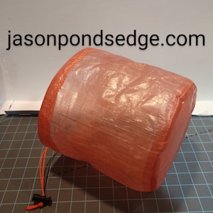 May include: A small, orange, mesh drawstring bag with a black cord lock. The bag is made of a lightweight, translucent material and is folded up.