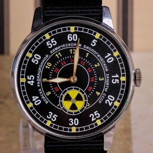 May include: A black wristwatch with a silver case and black band. The watch face has a black background with yellow and red markings. The watch face also has a yellow and black radiation symbol.