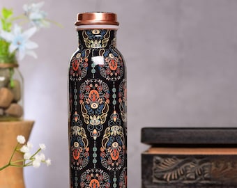 Op de afbeelding: Een zwarte koperen waterfles met een koperen deksel en een kleurrijk bloemenpatroon. De fles is versierd met een paisley-patroon in tinten oranje, blauw, groen en wit.