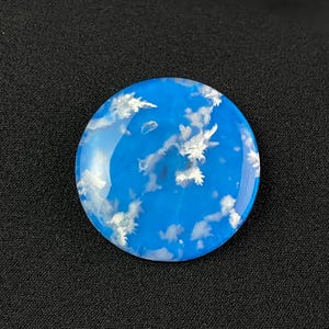 Könnte beinhalten: Ein runder, blauer und weißer Harz-Cabochon mit einem Wolkenhimmel-Design. Der Cabochon hat einen Durchmesser von etwa 2,5 cm.