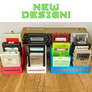 Peut inclure: Trois supports de rangement en plastique à étages de couleurs rouge, blanc et bleu, portant chacun le mot commodore sur le devant. Ces supports contiennent diverses cartouches de jeu vintage pour ordinateur Commodore 64, dont Donkey Kong et Forth 64.