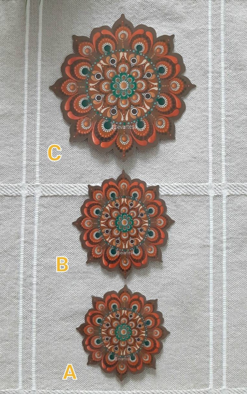 K&ouml;nnte beinhalten: Drei runde Holzmandalas mit komplizierten Mustern, die in Braun-, Orange- und Gr&uuml;nt&ouml;nen bemalt sind. Die Mandalas sind vertikal angeordnet, wobei das gr&ouml;&szlig;te oben und das kleinste unten ist. Die Mandalas sind mit A, B und C beschriftet.