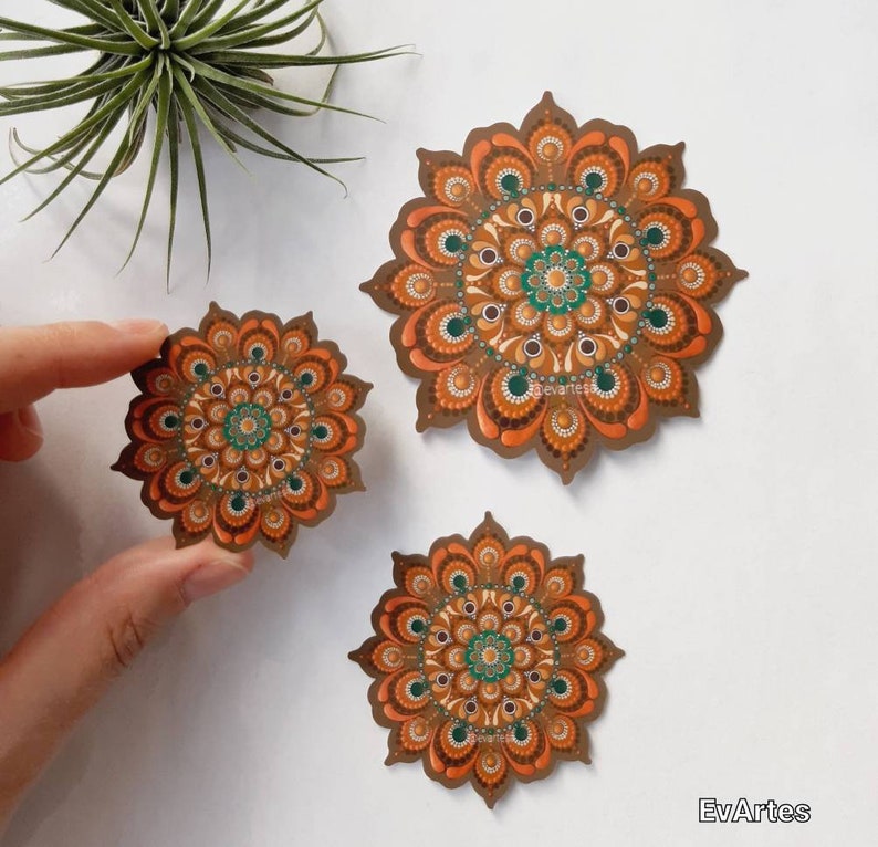 K&ouml;nnte beinhalten: Drei braune und gr&uuml;ne Mandala-Aufkleber mit komplizierten Designs. Der gr&ouml;&szlig;te Aufkleber befindet sich in der Mitte des Bildes, die beiden kleineren Aufkleber befinden sich links und rechts vom mittleren Aufkleber.