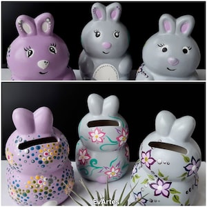 Puede incluir: Seis figuras de conejos de cerámica en lavanda y gris. Los conejos tienen caras pintadas y algunos están decorados con motivos florales. Las figuras son huchas, con una ranura en la parte posterior. El texto "EvArtes" es visible.