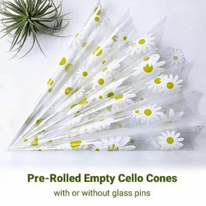 May include: A set of pre-rolled empty cello cones with a daisy print. The cones are clear and have a white background with yellow daisies. Pre-Rolled Empty Cello Cones with or without glass pins.