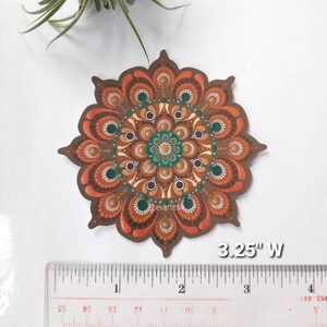 K&ouml;nnte beinhalten: Ein 3,25 Zoll breiter Mandala-Aufkleber in Braun-, Orange- und Gr&uuml;nt&ouml;nen. Das Mandala ist ein kreisf&ouml;rmiges Design mit komplizierten Mustern und Punkten.