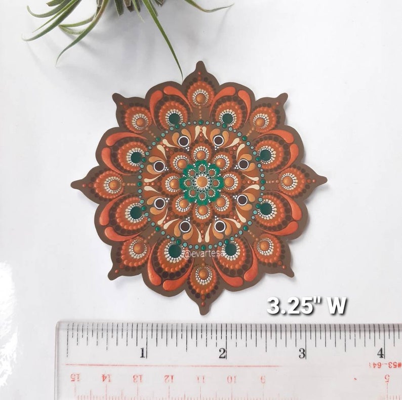 K&ouml;nnte beinhalten: Ein 3,25 Zoll breiter Mandala-Aufkleber in Braun-, Orange- und Gr&uuml;nt&ouml;nen. Das Mandala ist ein kreisf&ouml;rmiges Design mit komplizierten Mustern und Punkten.
