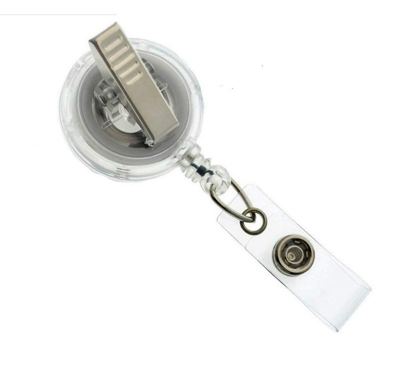 Op de afbeelding: Een transparante intrekbare badgehouder met een zilveren clip en een transparante plastic band. De band heeft een metalen ring en een transparante plastic badgehouder.
