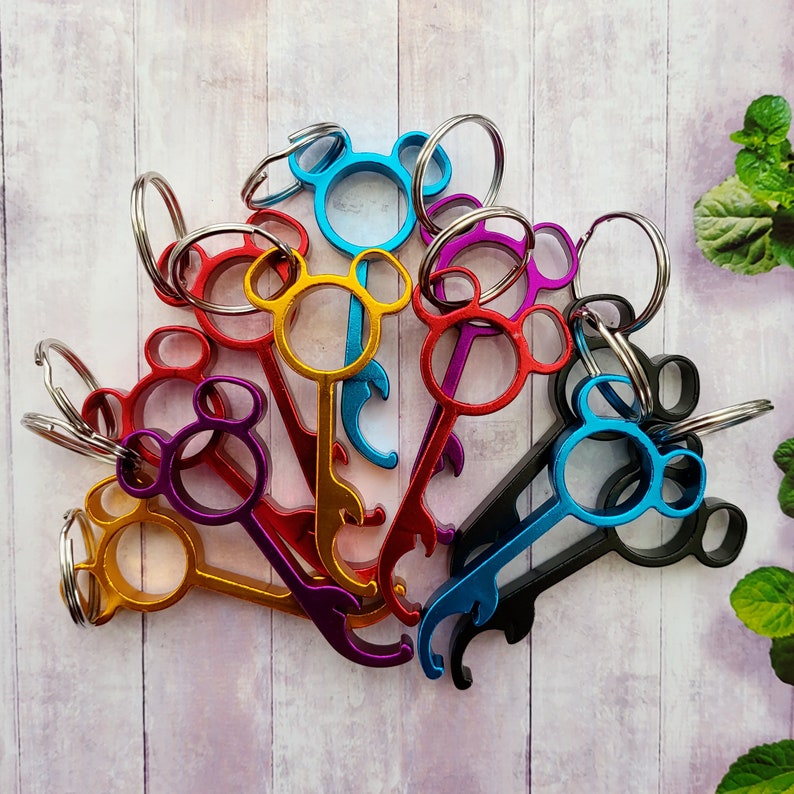 Puede incluir: Un conjunto de ocho llaveros coloridos con funciones de abridor de botellas. Cada llavero tiene forma de cabeza de oso de dibujos animados con un color diferente. Los llaveros est&aacute;n unidos a anillas de llaves.