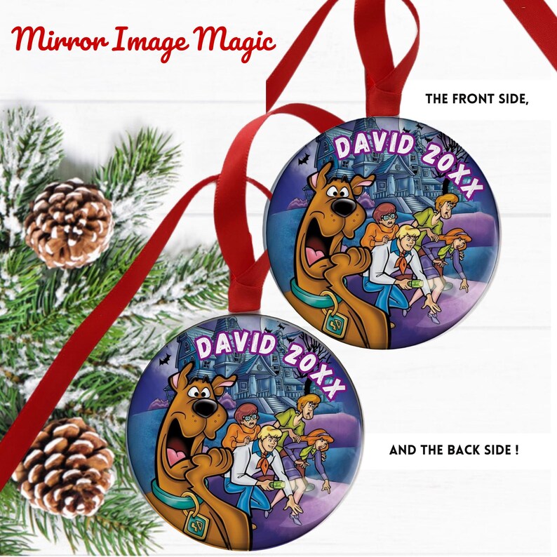 May include: Two round Christmas ornaments with a cartoon image of Scooby-Doo and the gang in front of a haunted house. The ornaments have red ribbons for hanging and the text "DAVID 20XX". The background includes pine needles and pine cones.