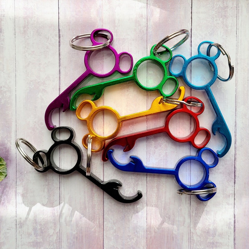 Puede incluir: Un conjunto de siete abridores de botellas de colores con un dise&ntilde;o de cabeza de Mickey Mouse. Cada abridor tiene un color diferente, incluyendo morado, verde, amarillo, rojo, azul y negro. Los abridores est&aacute;n unidos a llaveros.