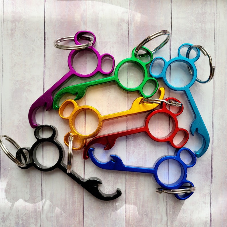 Puede incluir: Un conjunto de seis abridores de botellas de colores con forma de cabeza de Mickey Mouse. Cada abridor tiene un color diferente, incluyendo morado, verde, azul, rojo y amarillo. Los abridores est&aacute;n unidos a llaveros.