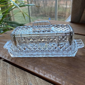 May include: A clear glass butter dish with a diamond pattern. The dish has a lid with a handle.