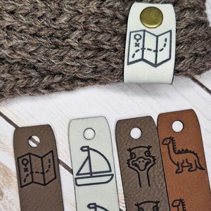 May include: A white ceramic mug with a black handle and the text "But First, Coffee" in a black, handwritten-style font. The mug is on a white surface.