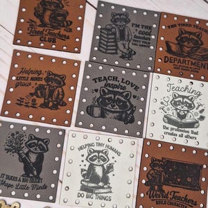 Peut inclure: Un ensemble de patchs carrés avec des illustrations de ratons laveurs et du texte. Les patchs sont de différentes couleurs, dont le marron, le gris et le blanc, avec des phrases comme "Tired Teachers Club" et "Teach, Love, Inspire". Pour les enseignants.