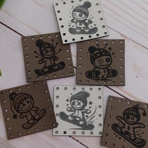 May include: Six square patches with stitched edges, each displaying a black and white illustration of a doll snowboarding. The patches are in shades of brown and white. The wooden sign at the bottom reads "@WeatheredWeaves".